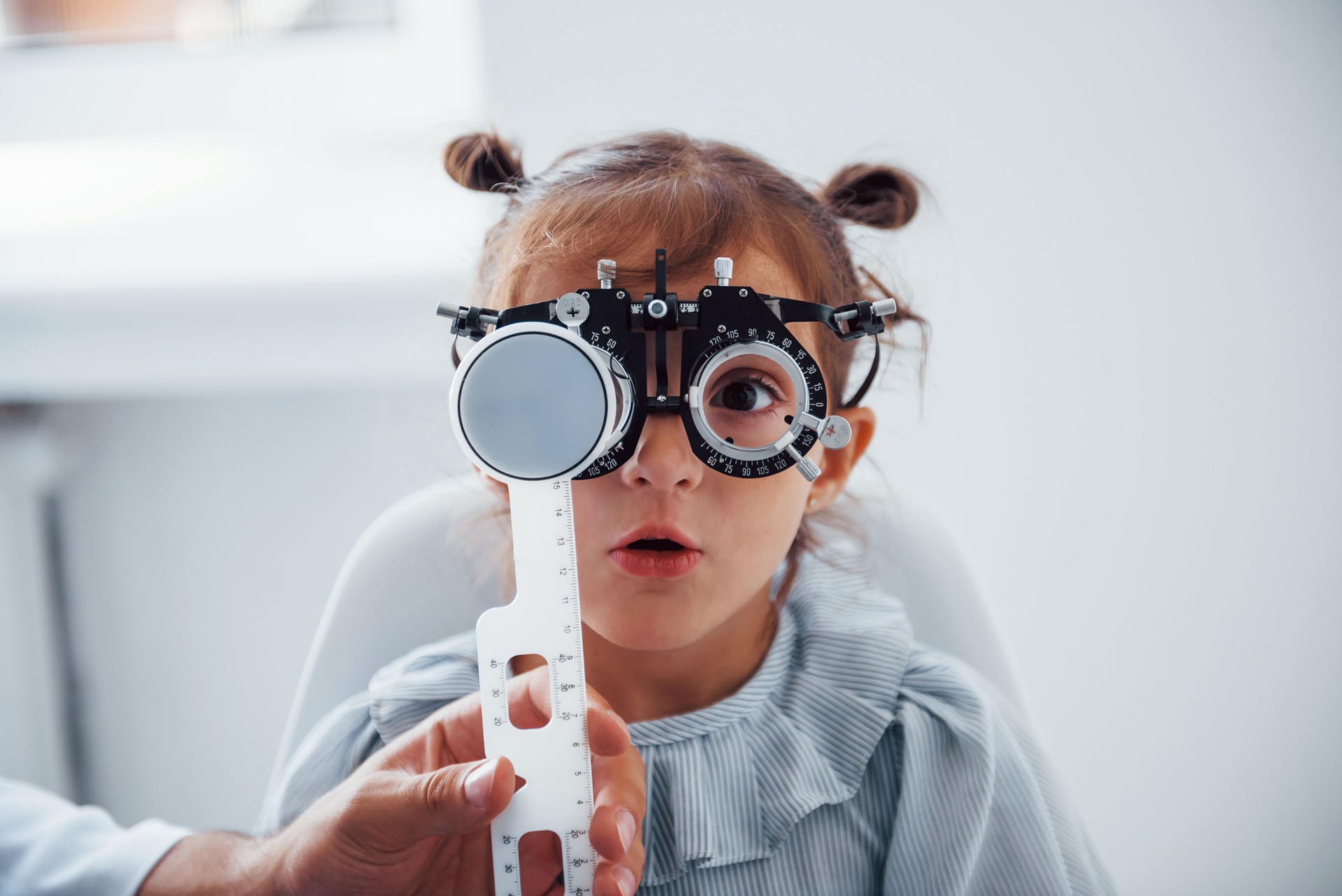 Little girl in eyewear in eye clinic has vision exam